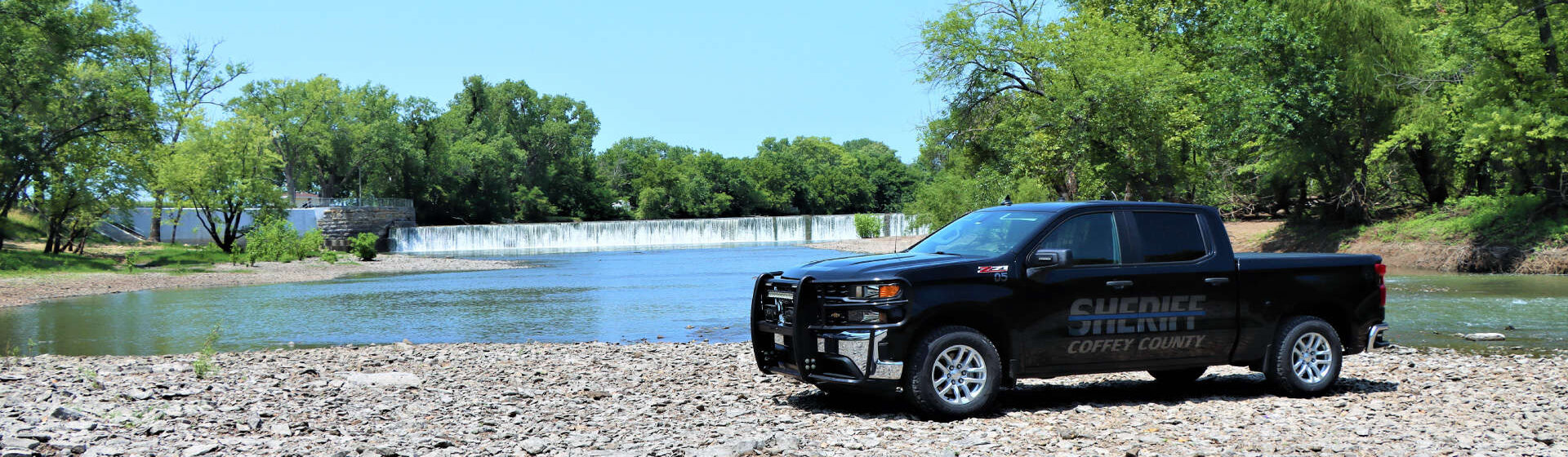 Sheriff truck parked on gravel and sitting next to a pond.